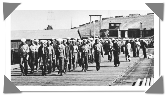 Black and white image of navy men marching on a carrier boat deck